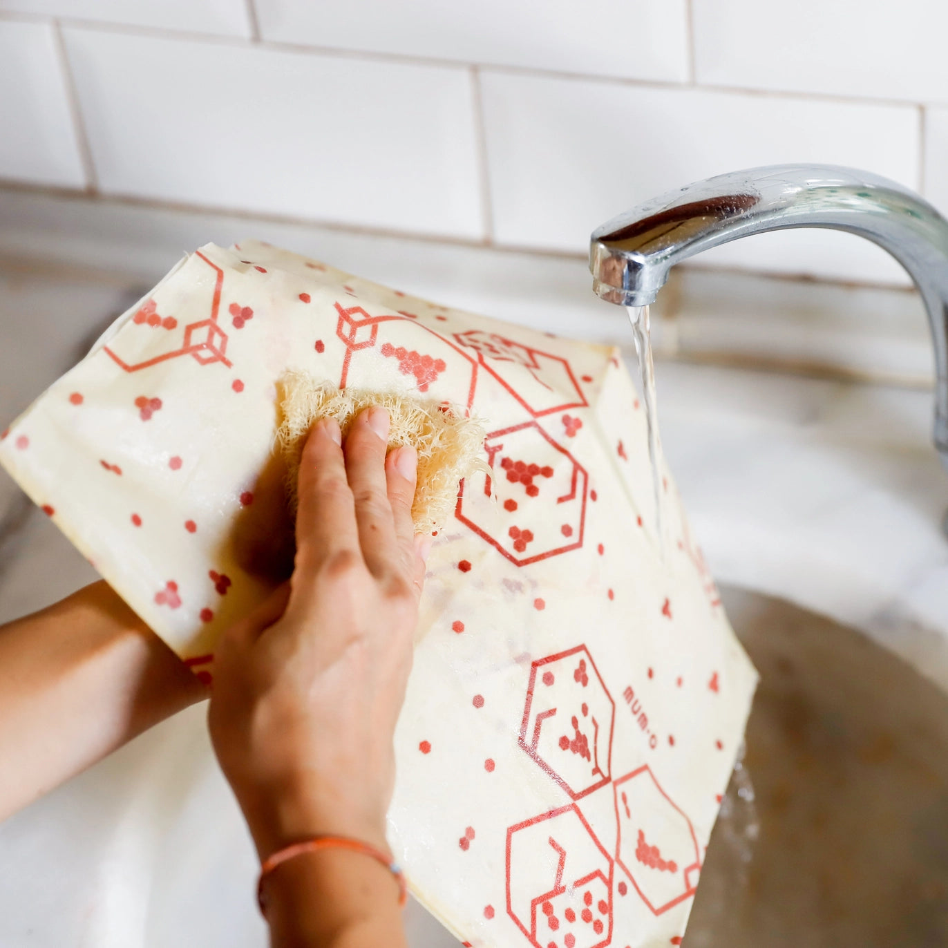 Person cleaning a cutting board with a cloth in a kitchen sink.