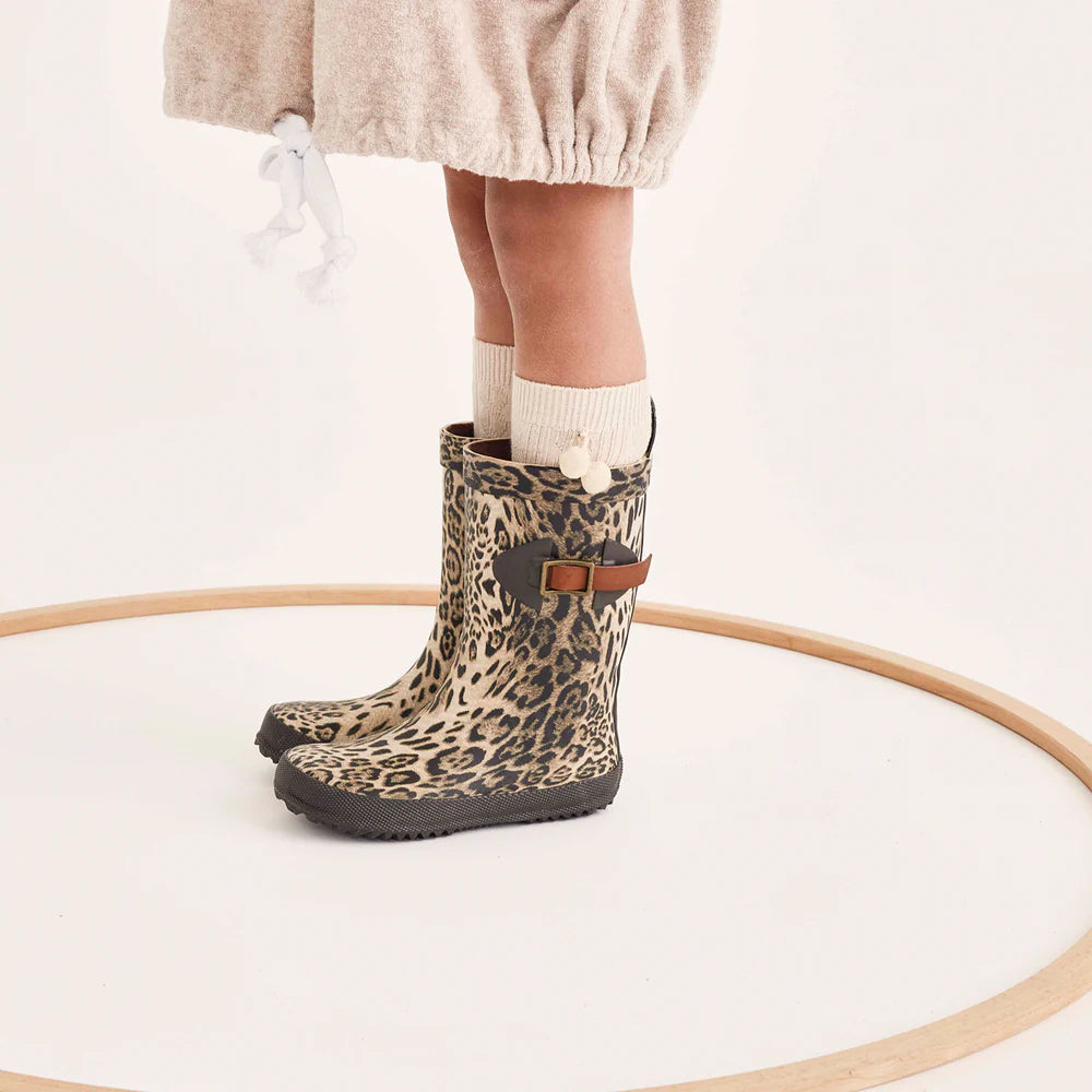 Leopard print rain boots with a brown strap worn by a person