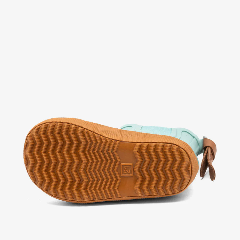 Close-up of a child's boot with brown sole and light blue upper on a white background