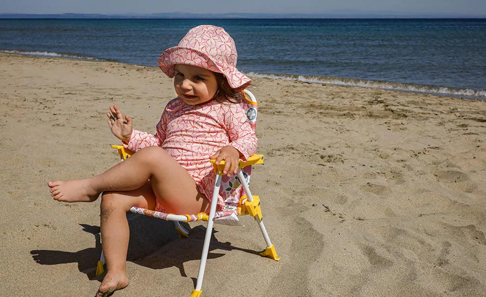 Child sitting on a beach chair at the beach.