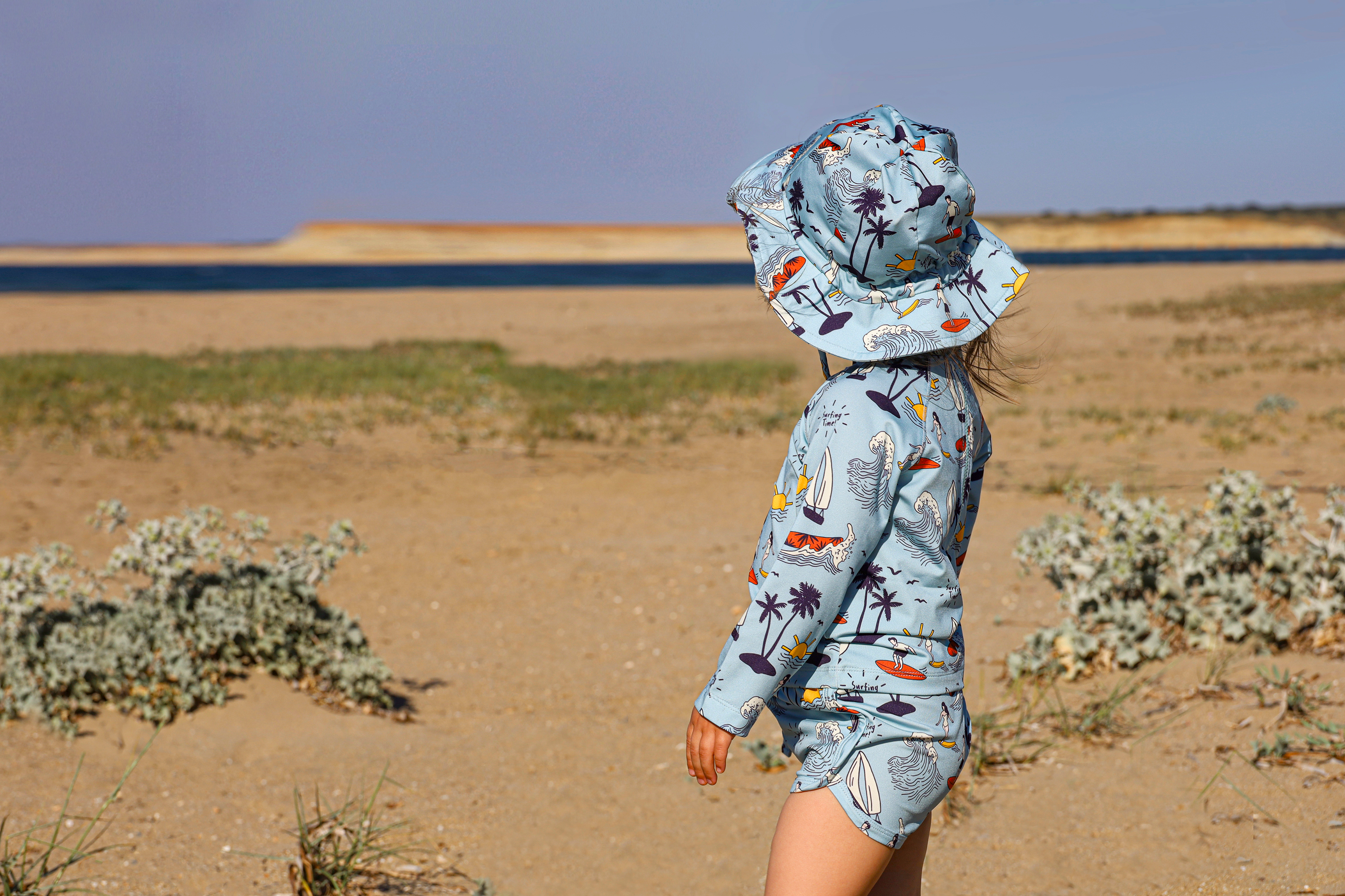 Person wearing a hooded jacket with a tropical pattern in a desert setting.