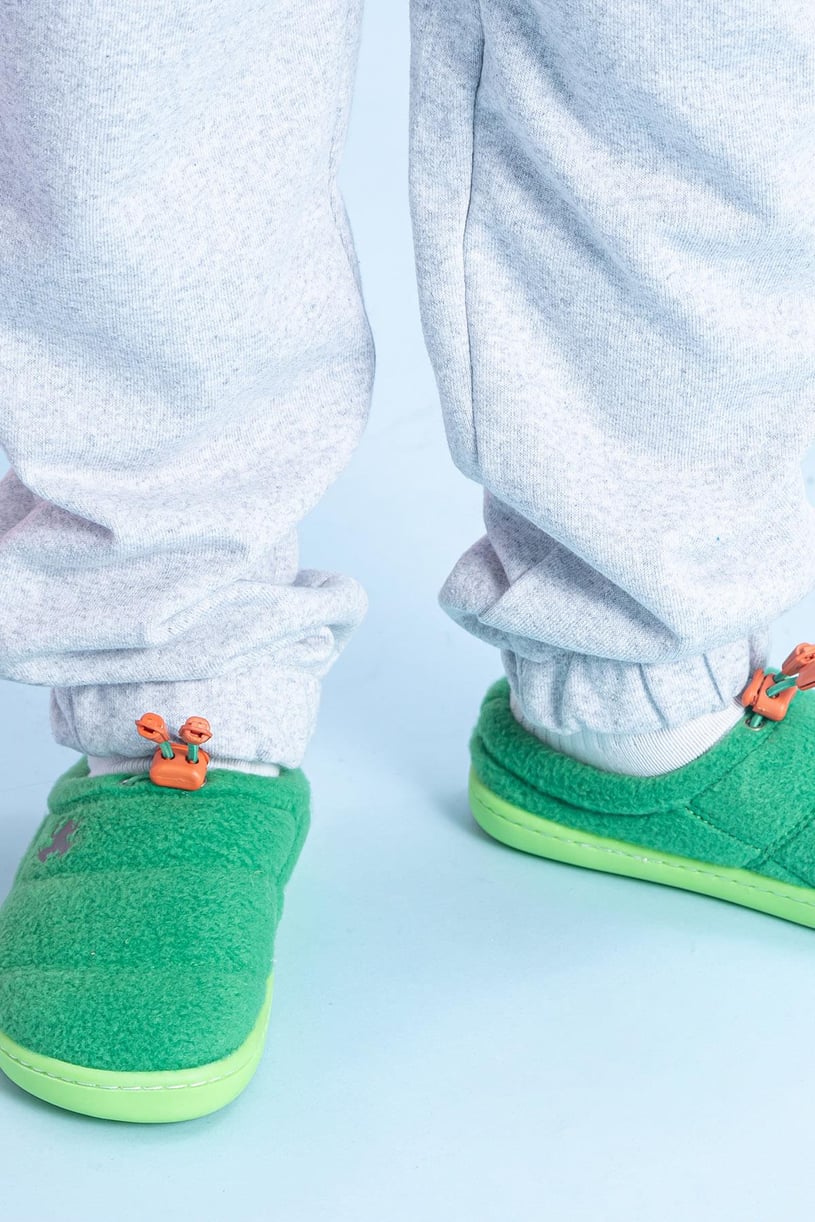 Close-up of a boy wearing a pair of green barefoot shoes for kids with a logo and laces