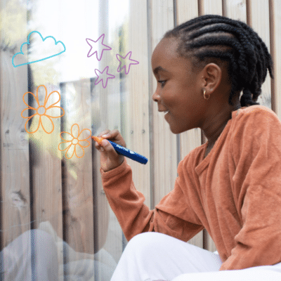 Child drawing on a glass window with colorful markers